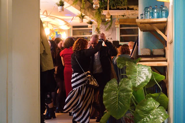 Interior de Ohana de noche, gente, plantas colgantes y luces cálidas